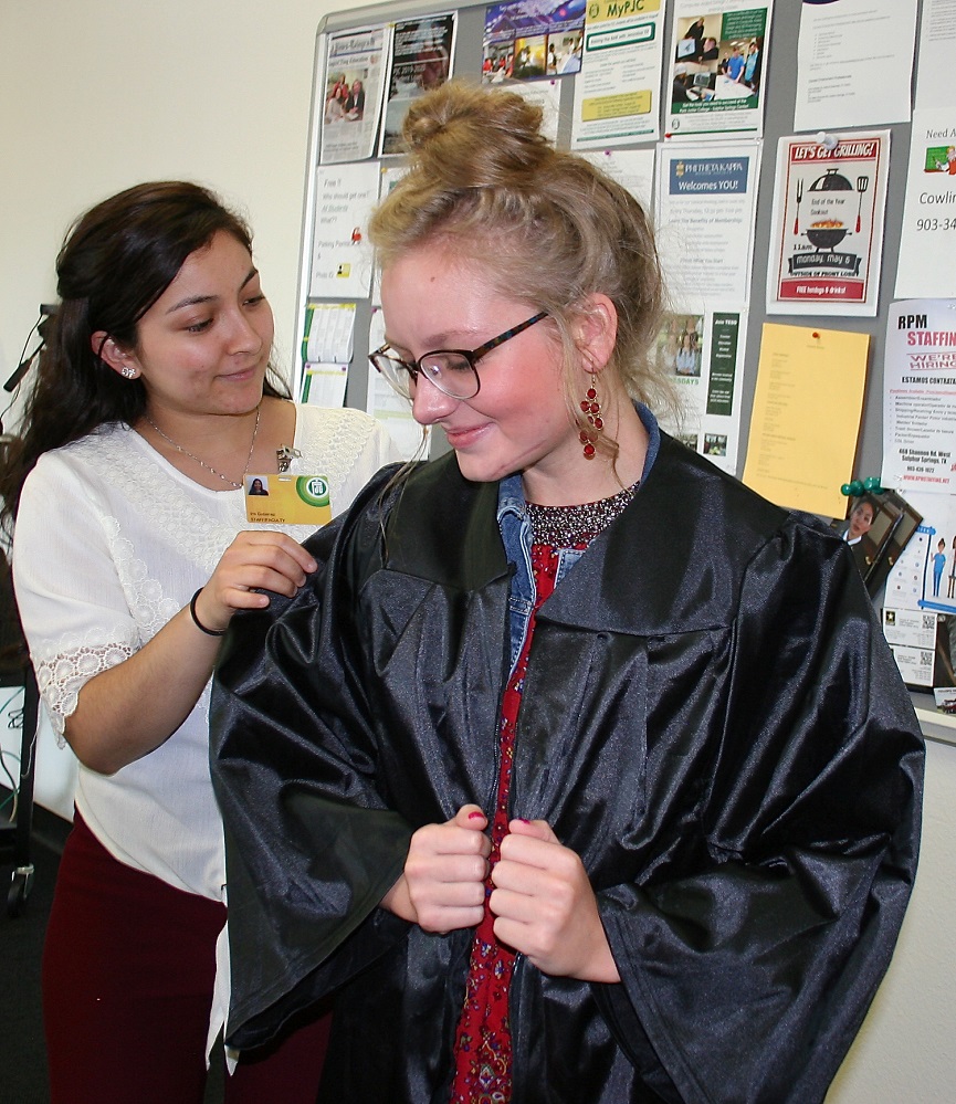 GRADUATION TIME PJC-Sulphur Springs Center Assistant Director Iris Gutierrez helps student Melody Shannon try on a graduation robe
