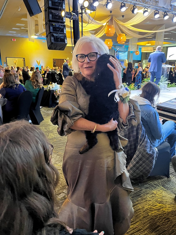 Chair of the Hopkins County Health Care Foundation Board of Directors Pam Black is shown here with a furry friend at the 2025 Gala, Serendipity by the Sea. Dr. Laura Kosub and Lake Country Labradoodles donated the puppy which was included in the live auction. To get your tickets or sponsor the 2026 Gala, visit Gala2026.GiveSmart.com or call the Foundation at 903-438-4799.