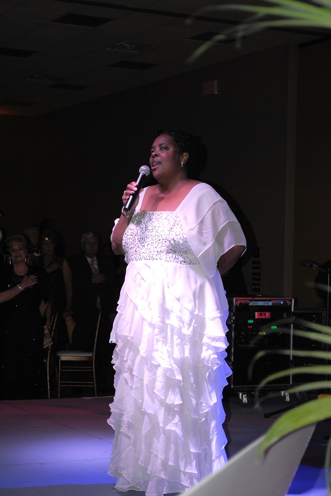 PR 31 Photo 1 – In 2015, Pamela Clayton-Wright sang the National Anthem at the beginning of the program for the Gala. Leesa and Brian Toliver were the chairs, and the theme was The Great Gatsby. The proceeds from that year’s Gala were used to purchase 3 flex coils, 3 telemedicine units, and EMS vehicles for the local hospital at the time, Hopkins County Memorial. The Honorees were Wanda and Wayne Galyean. There are still opportunities to support the 20th anniversary Gala. Visit Gala2026.GiveSmart.com for all of the options.
